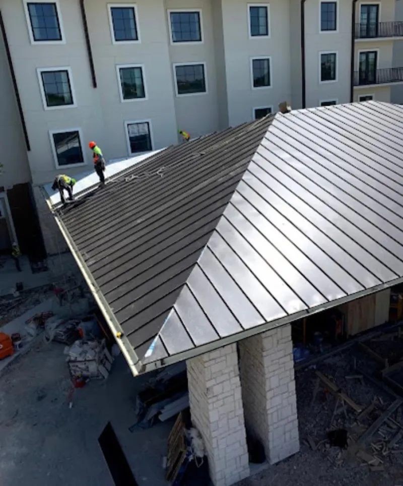 Crew installing standing seam metal roof panels on a commercial project in Sanford